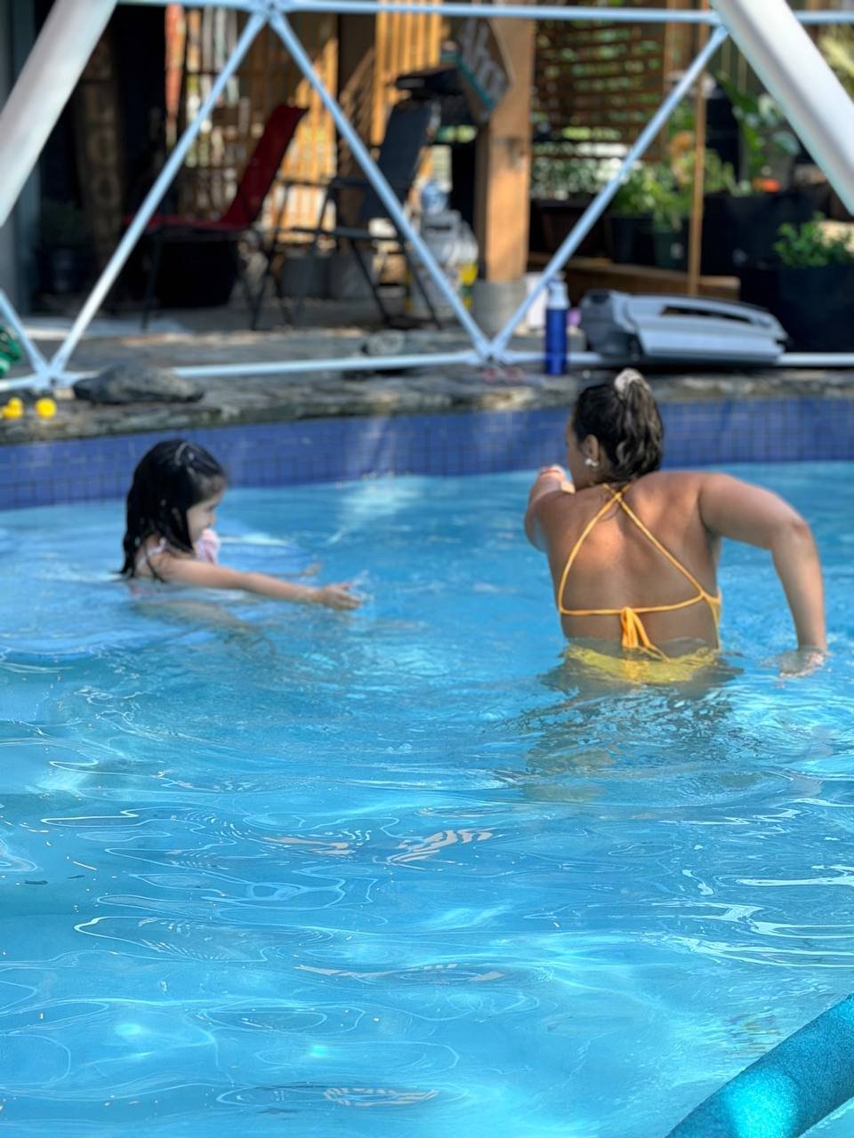 Child smiling on a kickboard beside her coach